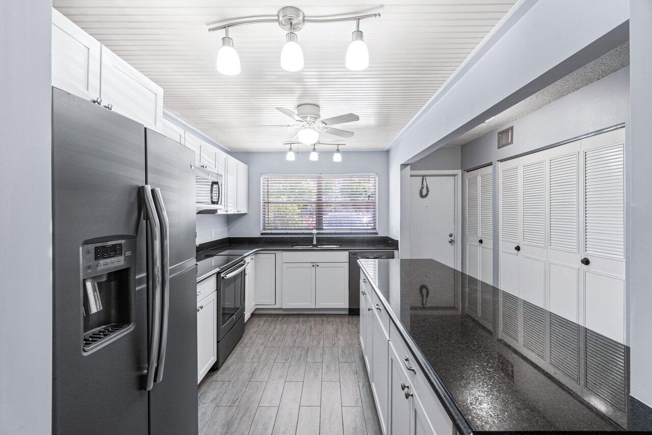 a large kitchen with a large window a refrigerator and stainless steel appliances