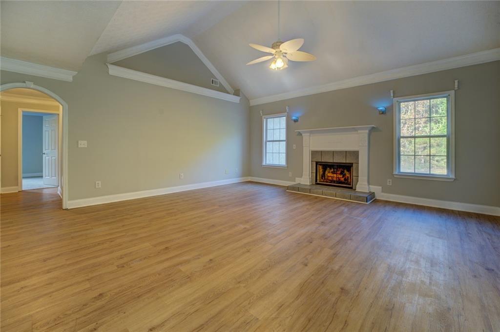 an empty room with wooden floor fire place and windows