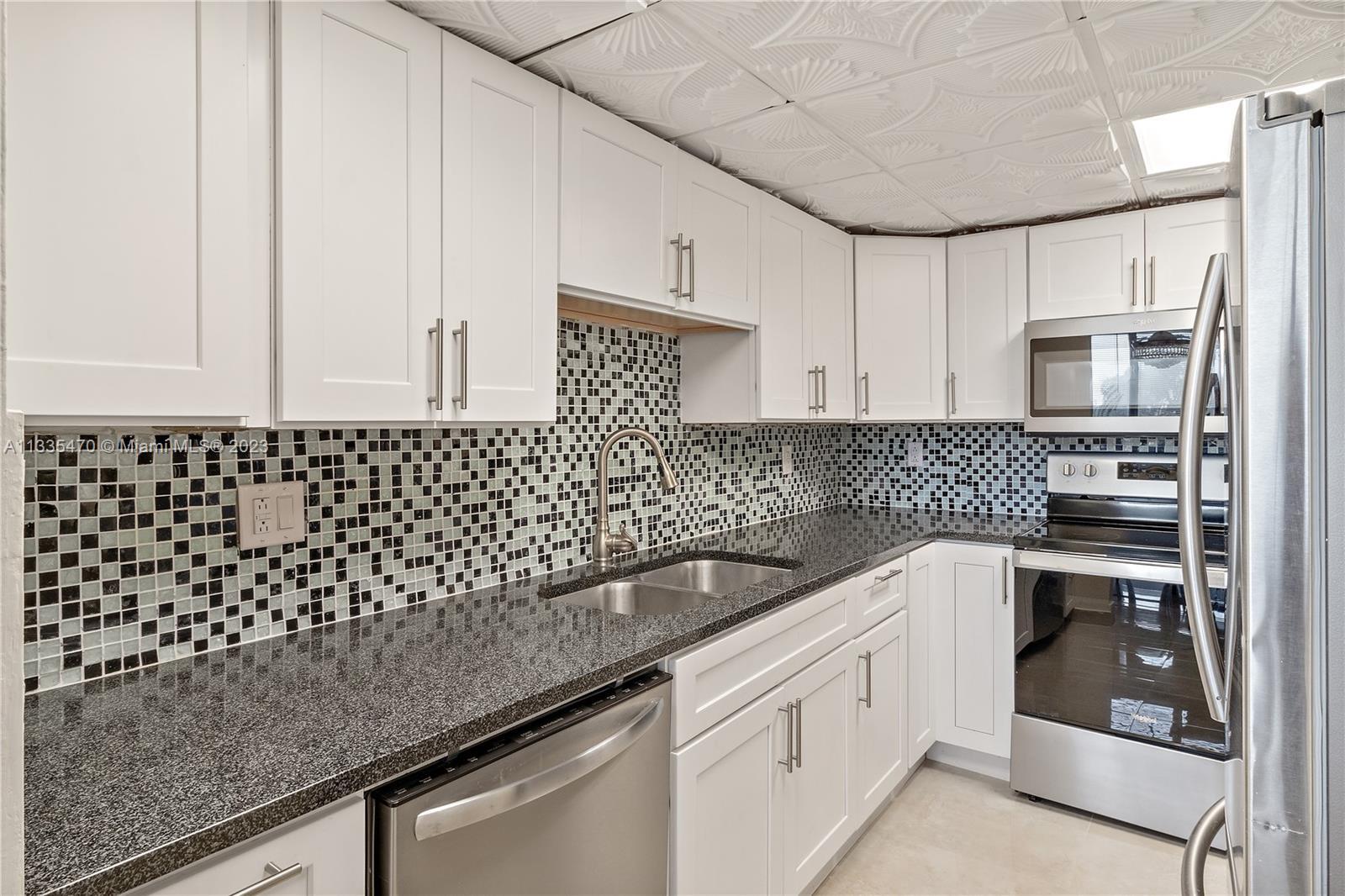 a kitchen with granite countertop white cabinets and white appliances