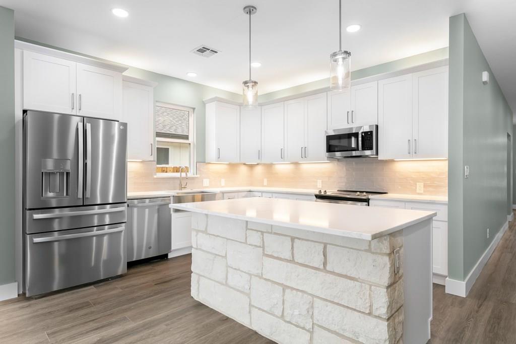 a kitchen with kitchen island white cabinets and stainless steel appliances