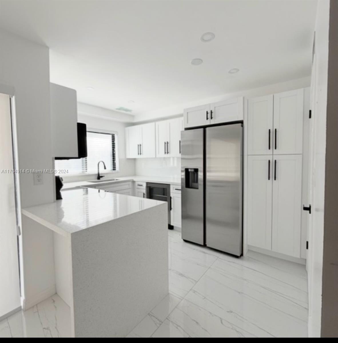 a kitchen with stainless steel appliances a refrigerator sink and white cabinets