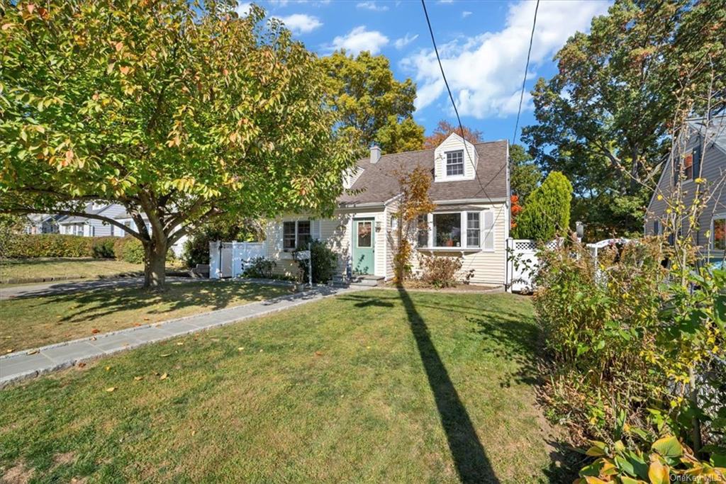 a front view of a house with a garden and trees