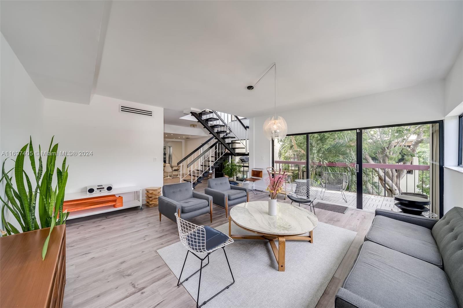 a living room with furniture kitchen view and a large window