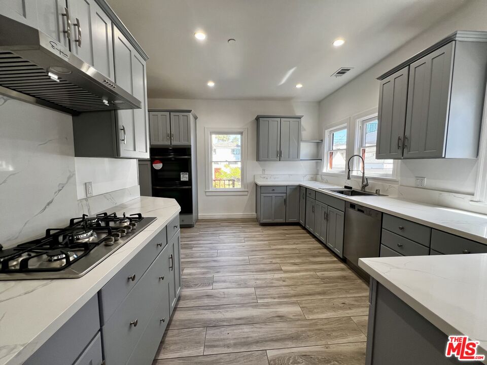 a kitchen with stainless steel appliances kitchen island granite countertop a stove sink and cabinets