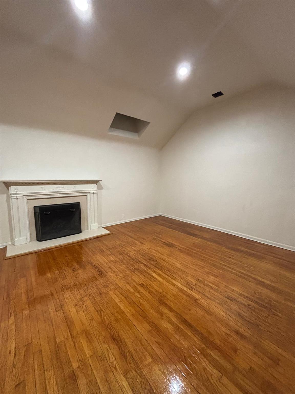 Unfurnished living room with hardwood / wood-style floors and vaulted ceiling