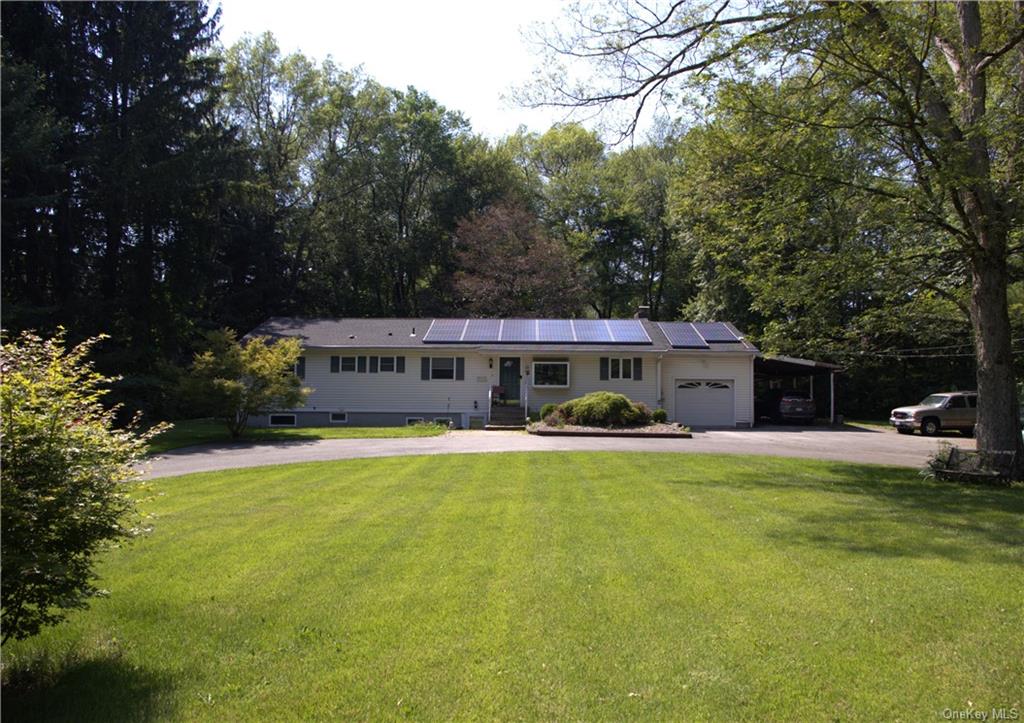 Single story home featuring solar panels, a garage, and a front yard