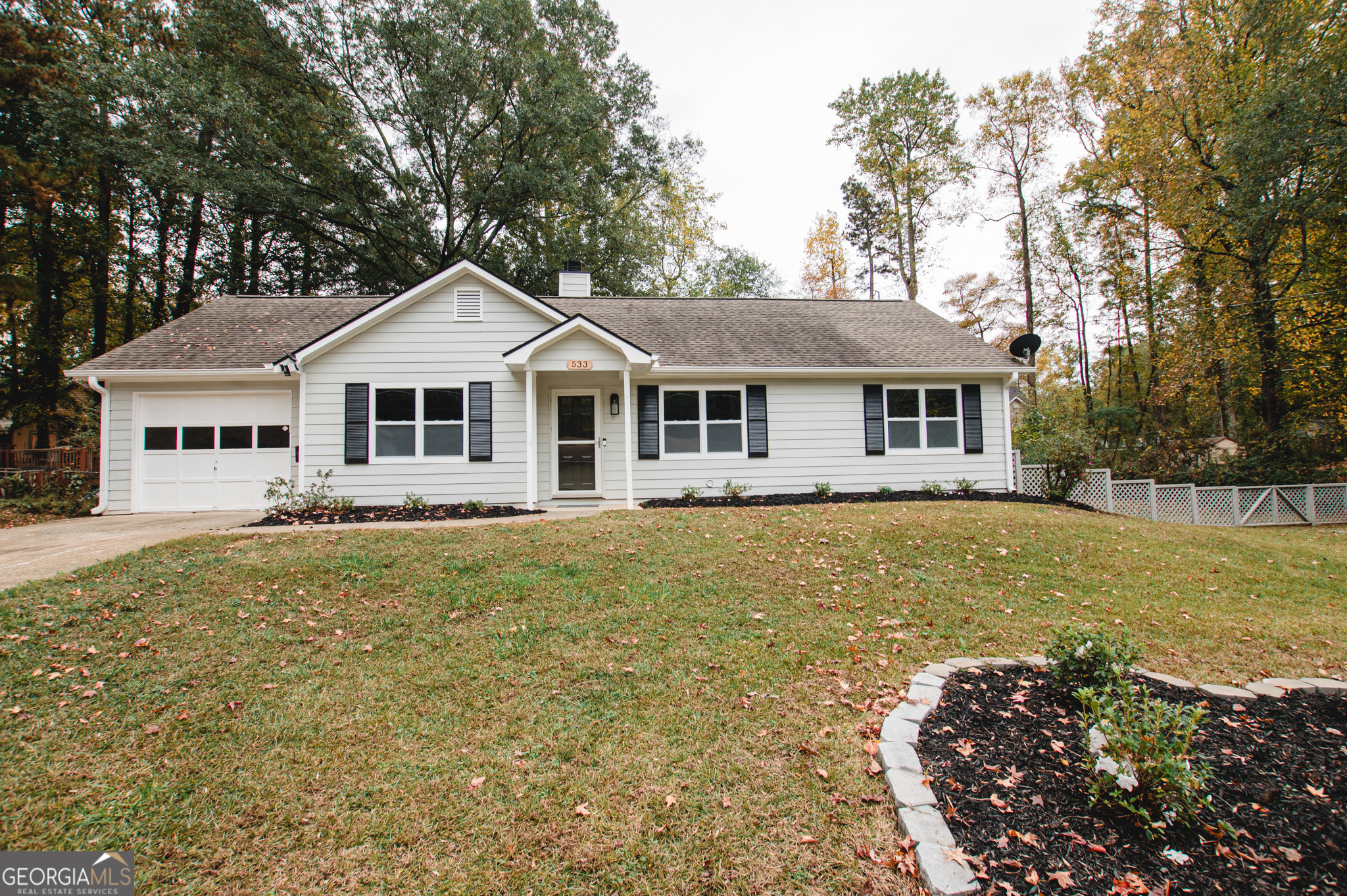 a front view of a house with a garden and trees