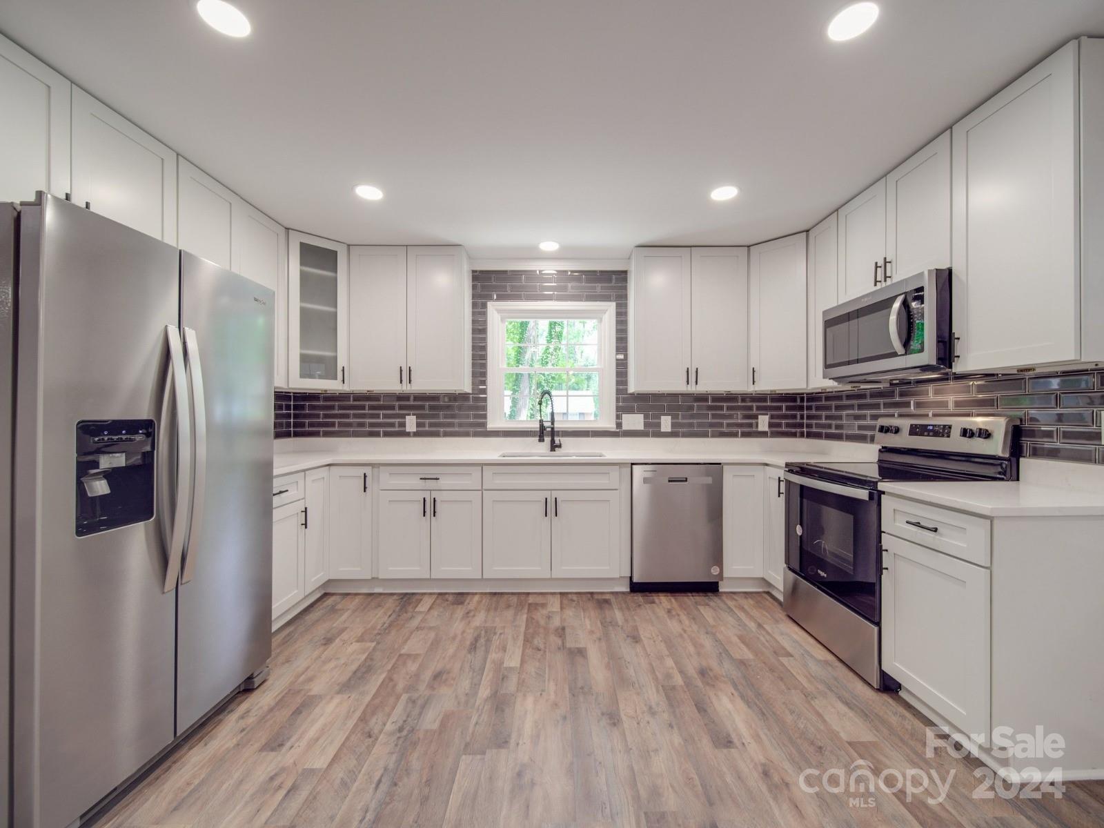 a kitchen with stainless steel appliances a refrigerator sink and microwave