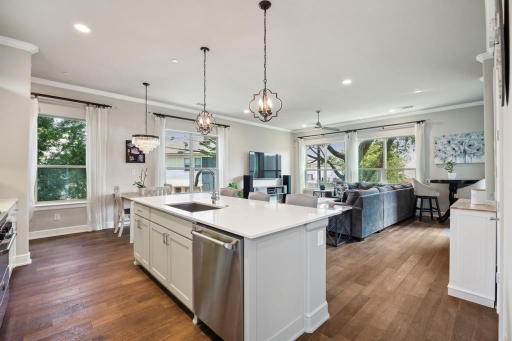 a large kitchen with kitchen island a large counter top a sink stainless steel appliances and cabinets