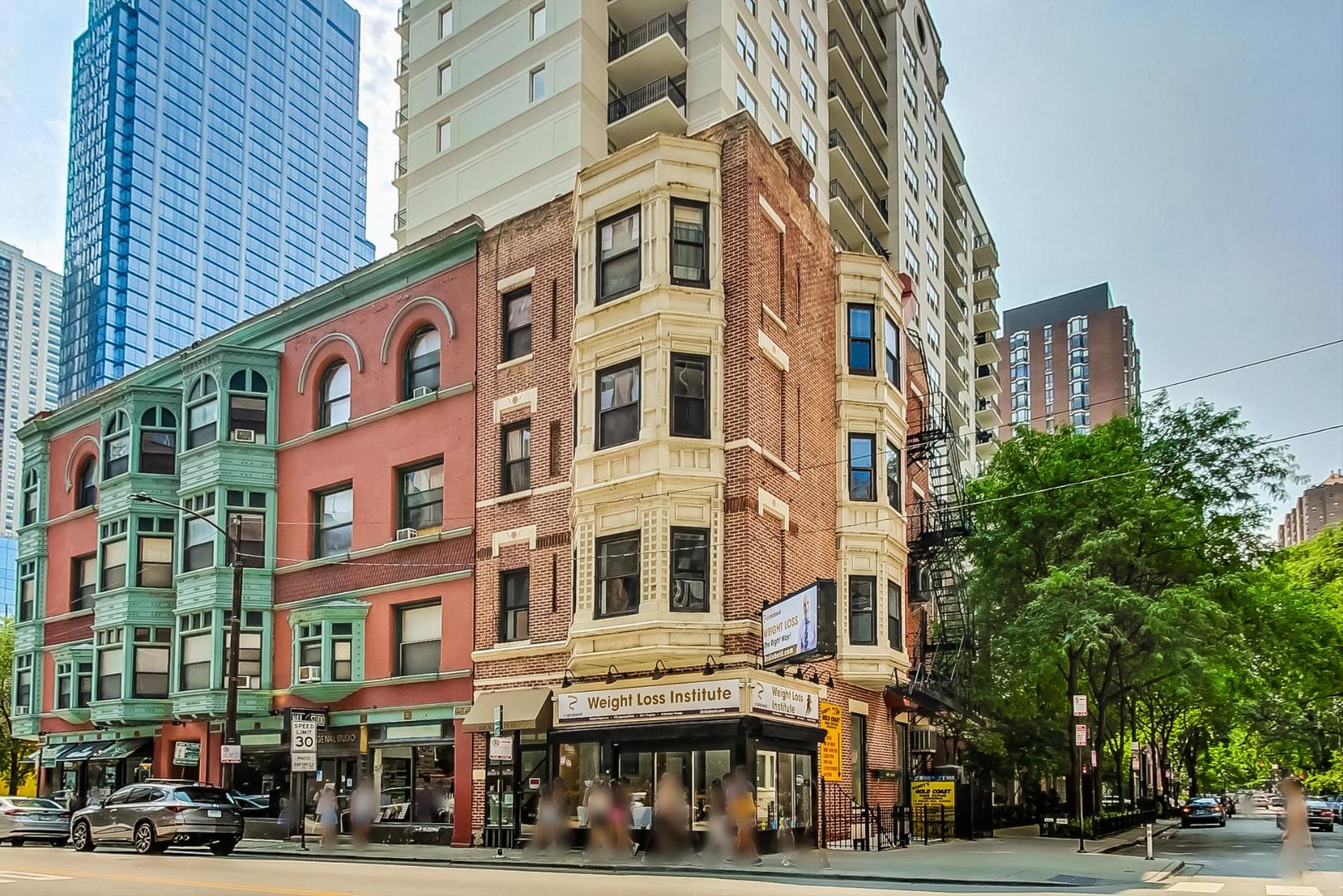 a front view of a building with lot of cars and trees