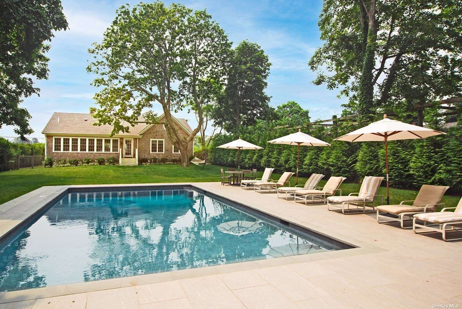 a view of swimming pool with lawn chairs under an umbrella