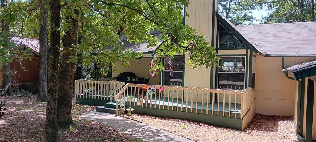 a view of a wooden house with large trees and wooden fence