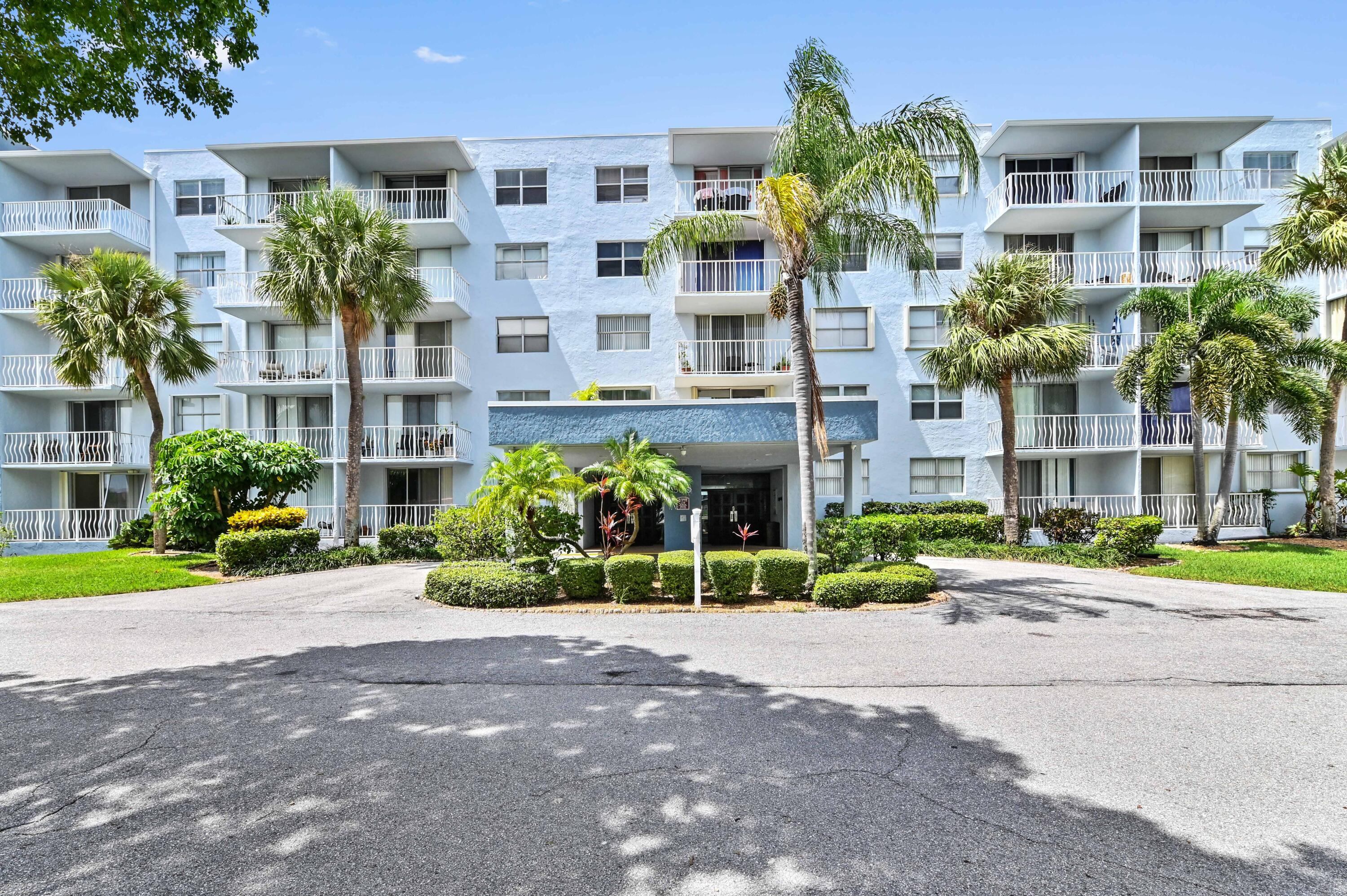 a front view of a multi story residential apartment building with yard and green space