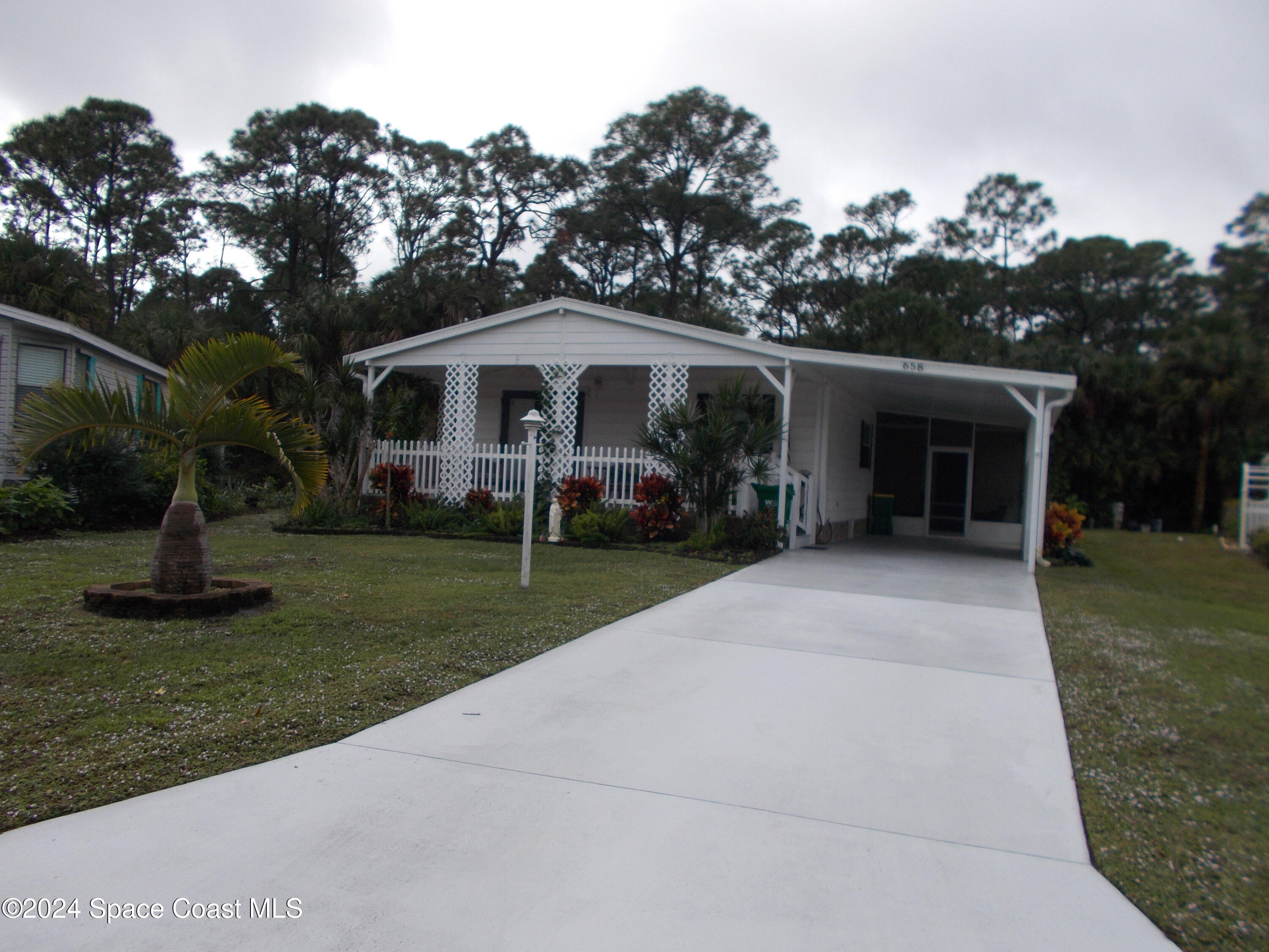 a front view of a house with a garden and trees