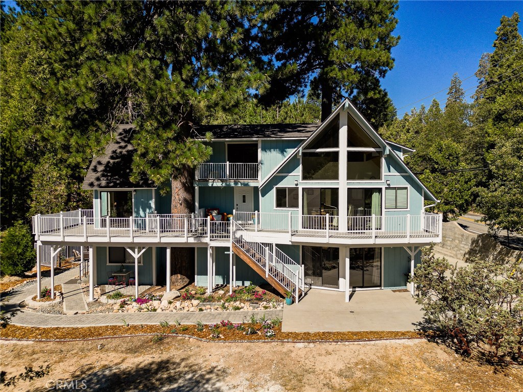 a front view of a house with a wooden deck and a large tree