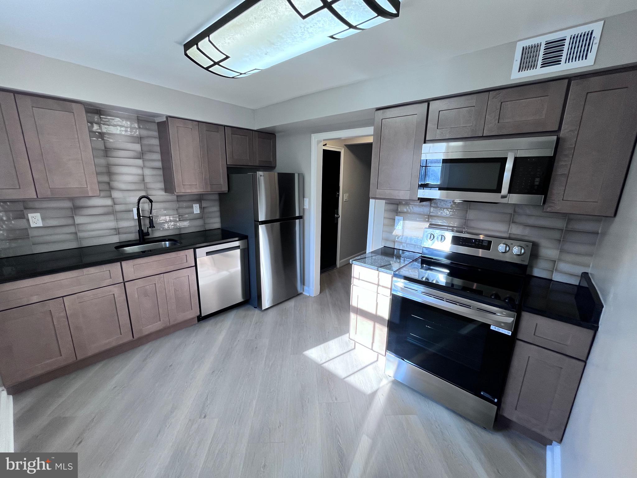 a kitchen with stainless steel appliances kitchen island granite countertop a stove a sink and a refrigerator