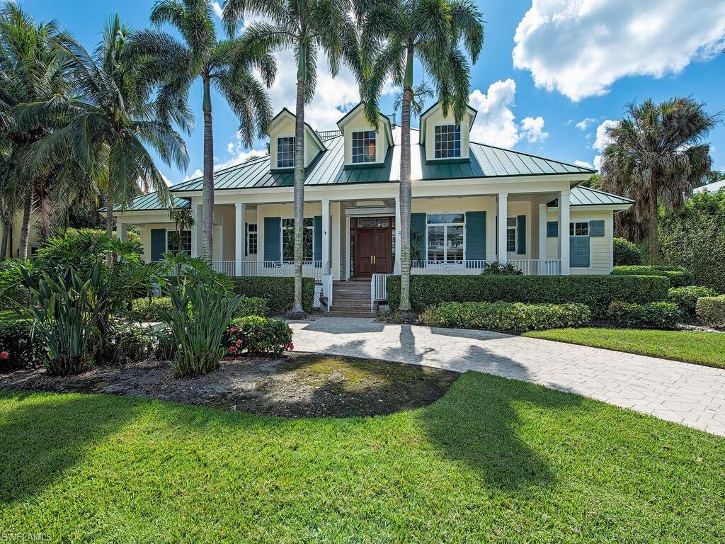 a view of a white house next to a yard with palm trees