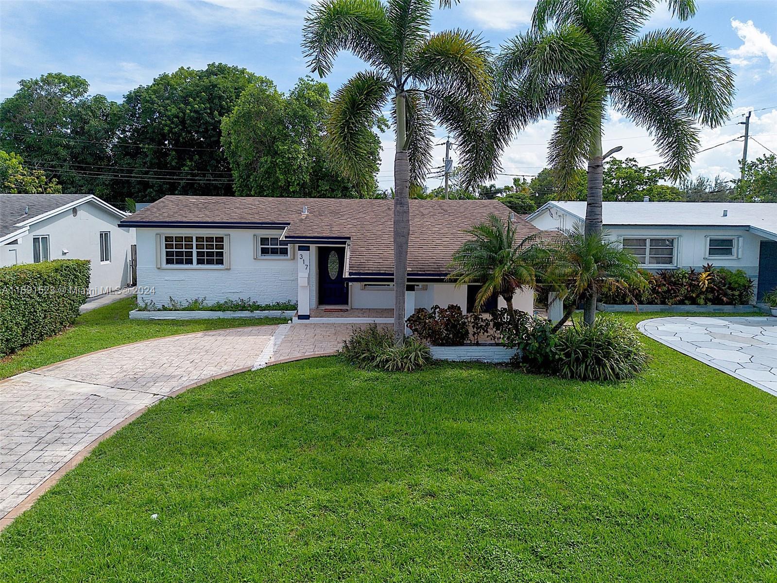 a view of a house with a yard and palm trees