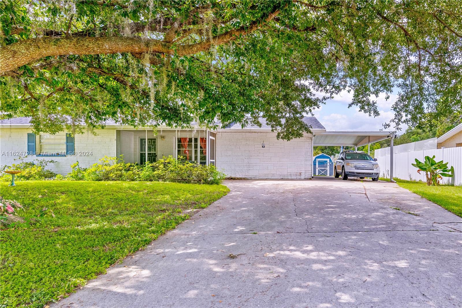 a view of a house with a yard and a large tree