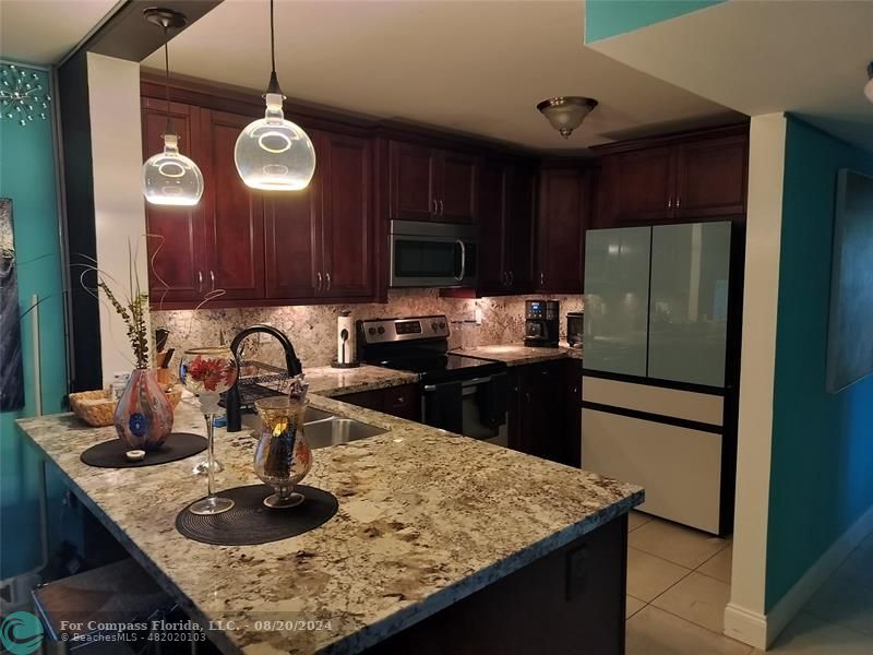 a kitchen with stainless steel appliances granite countertop a sink dishwasher a refrigerator and a stove