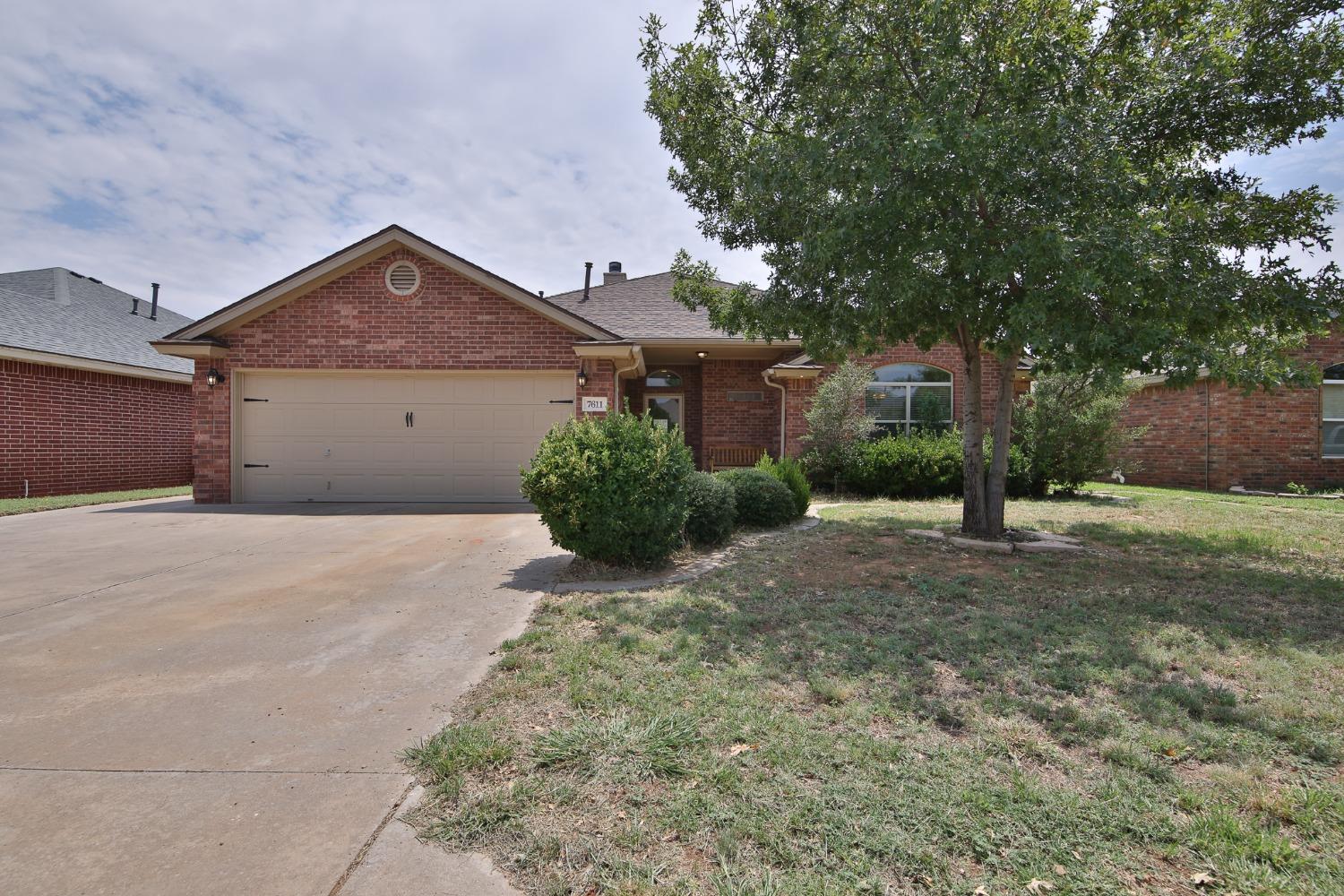 a front view of a house with a yard and tree