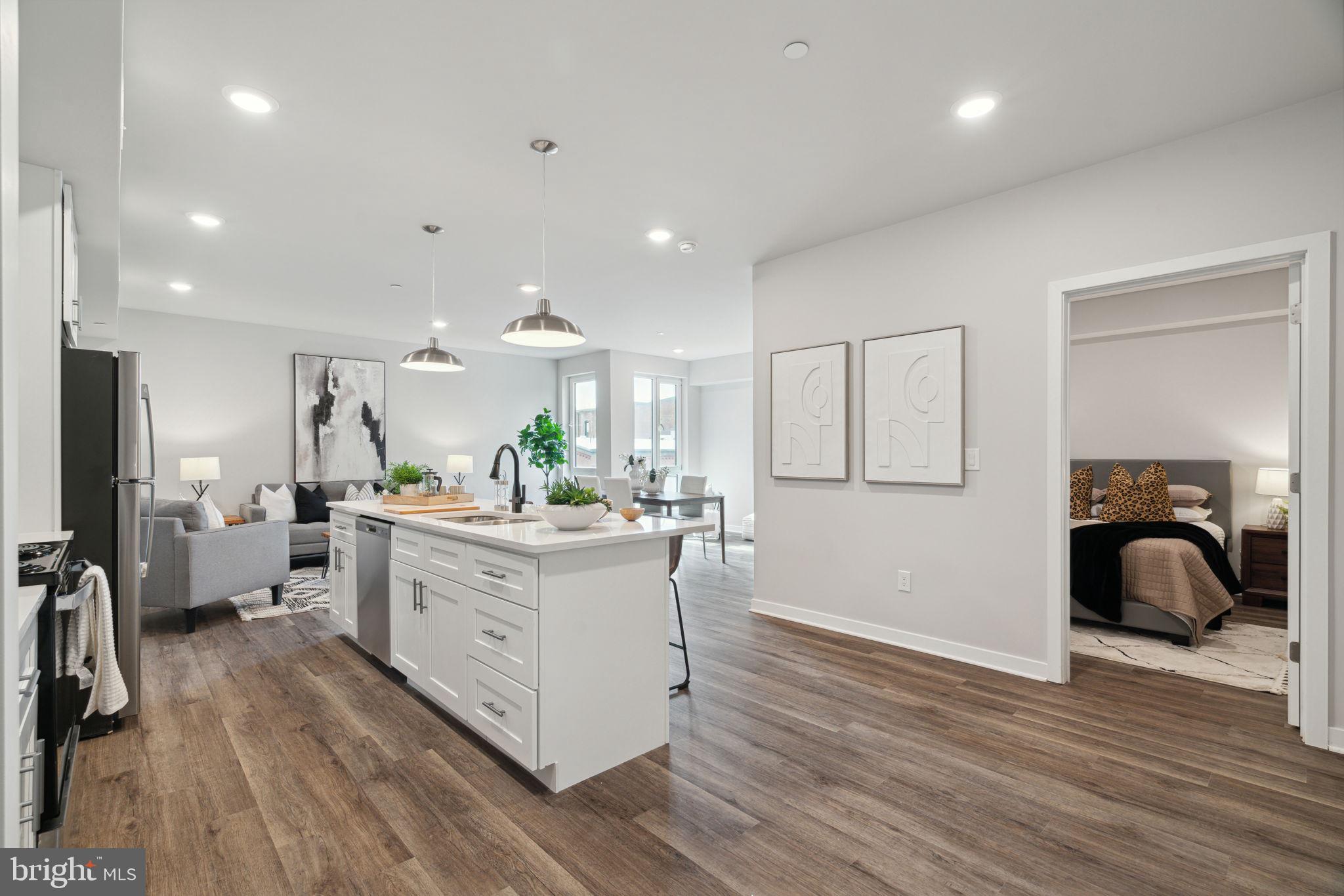 a large white kitchen with stainless steel appliances granite countertop a lot of counter space and a wooden floors