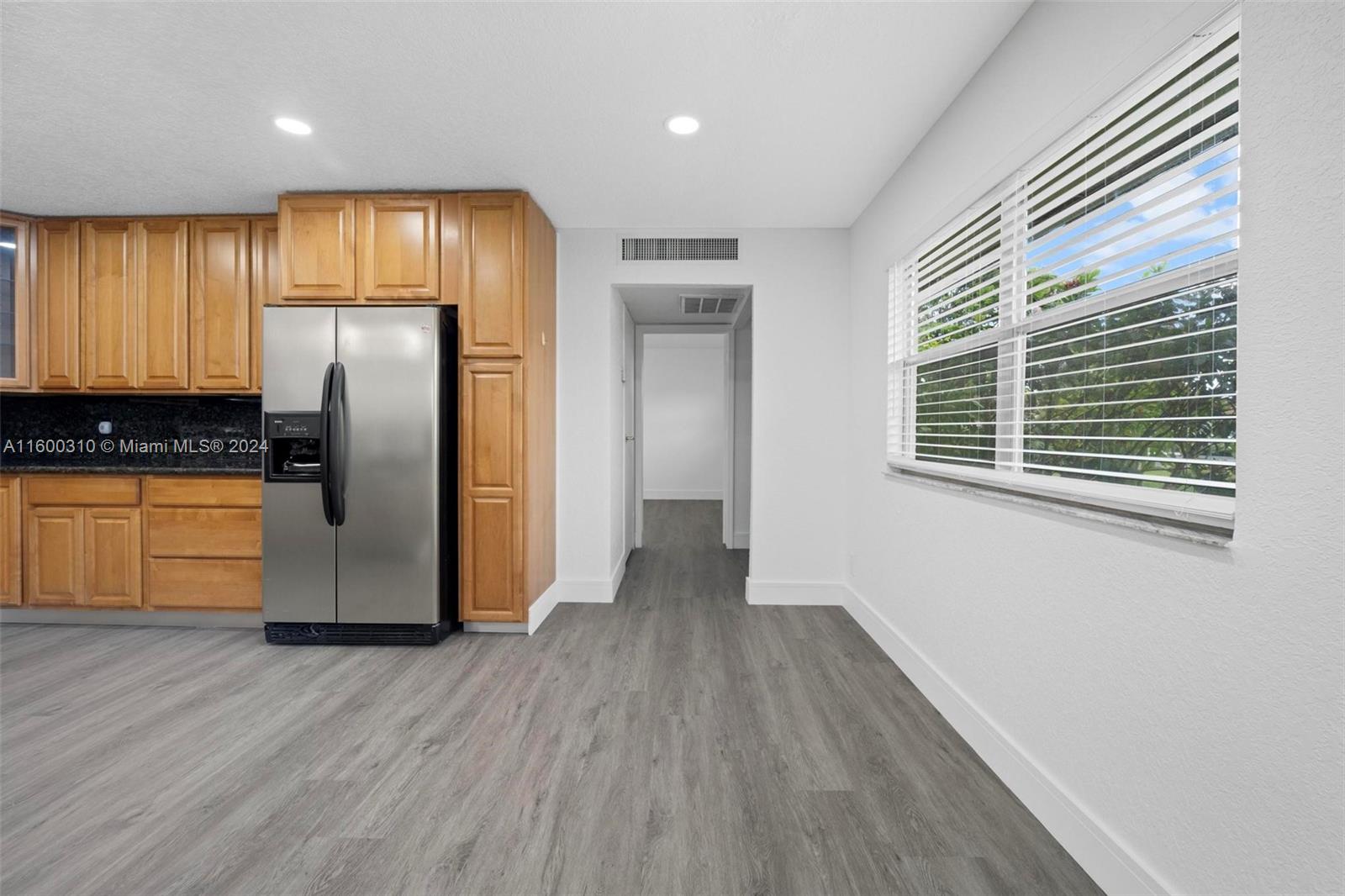 a view of a kitchen with a fridge and wooden floor