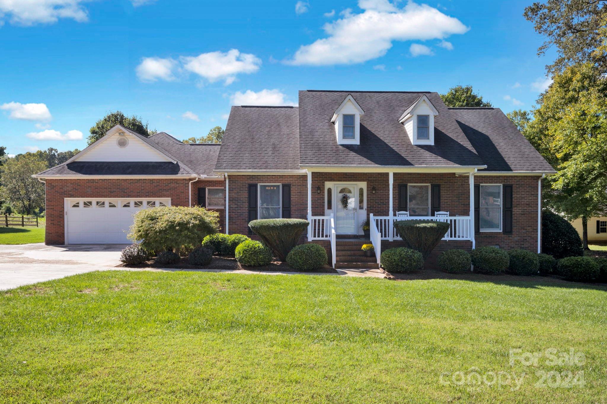 a front view of a house with a yard and potted plants