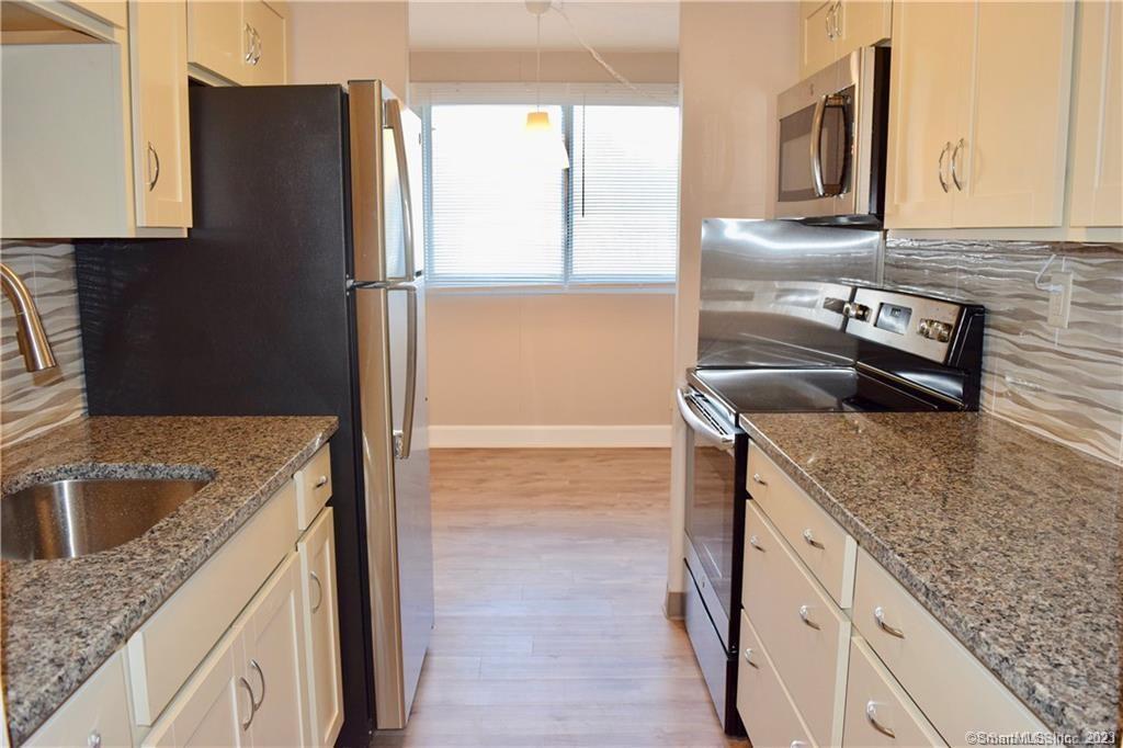 a kitchen with granite countertop a sink and a refrigerator