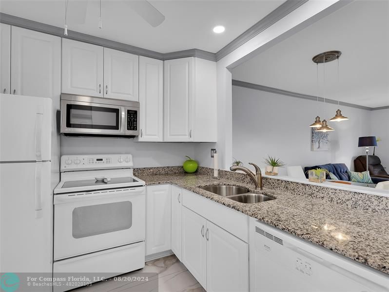 a kitchen with granite countertop a sink a stove and cabinets