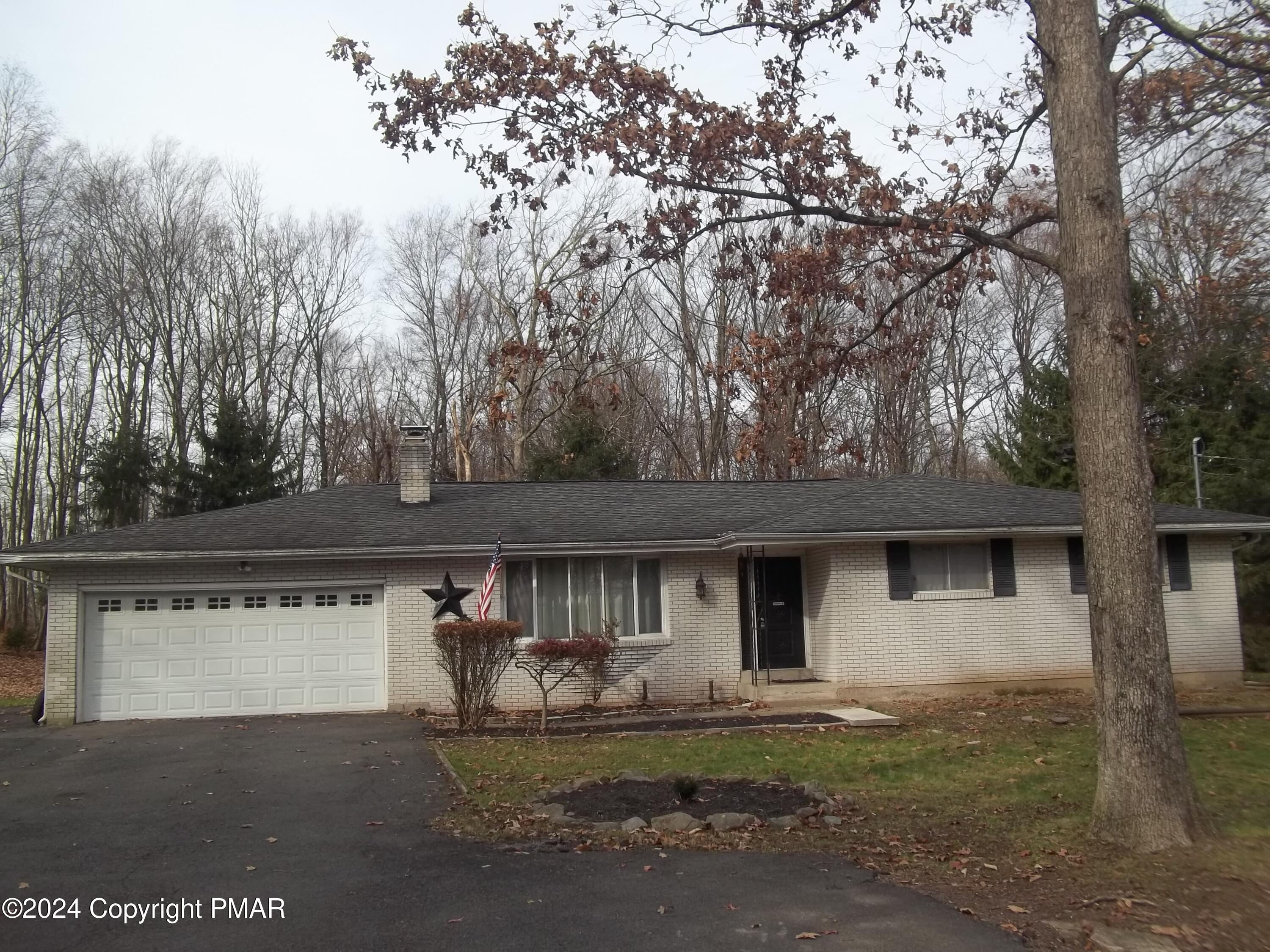 a front view of house with yard and trees in the background