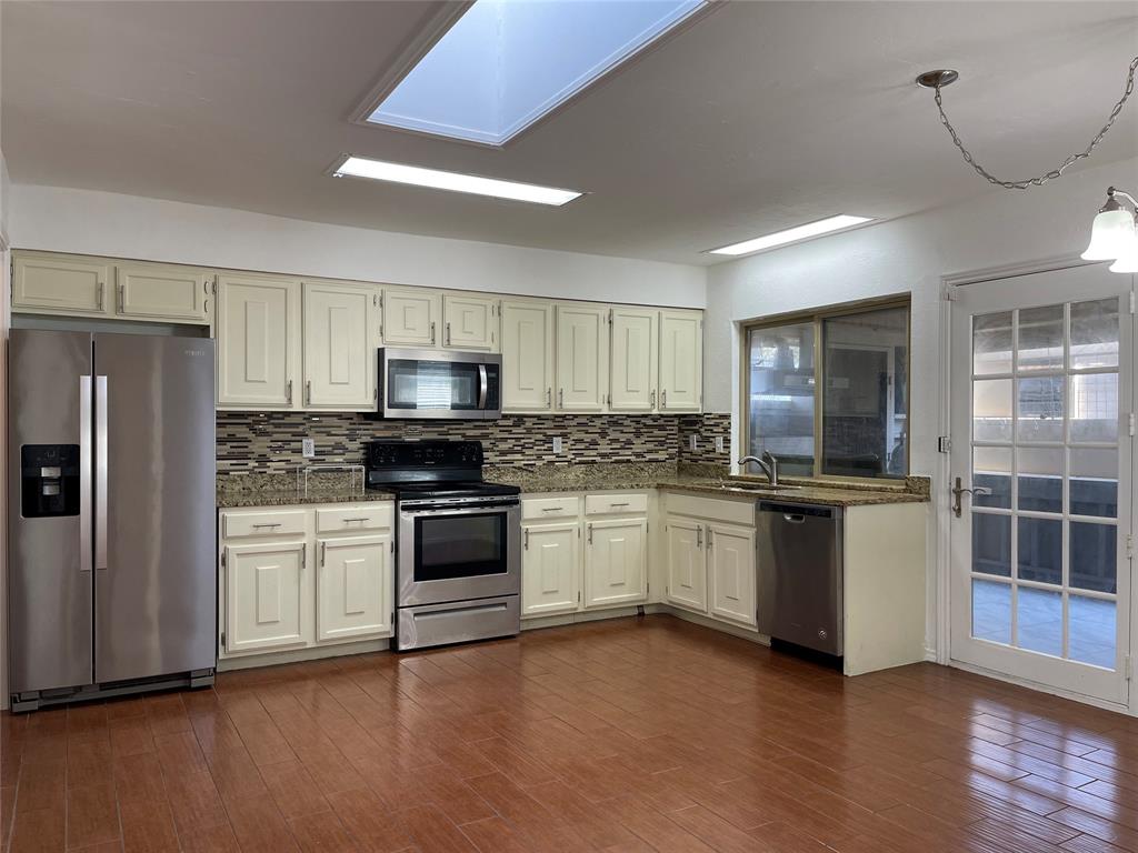 a kitchen with granite countertop a refrigerator stove top oven and sink