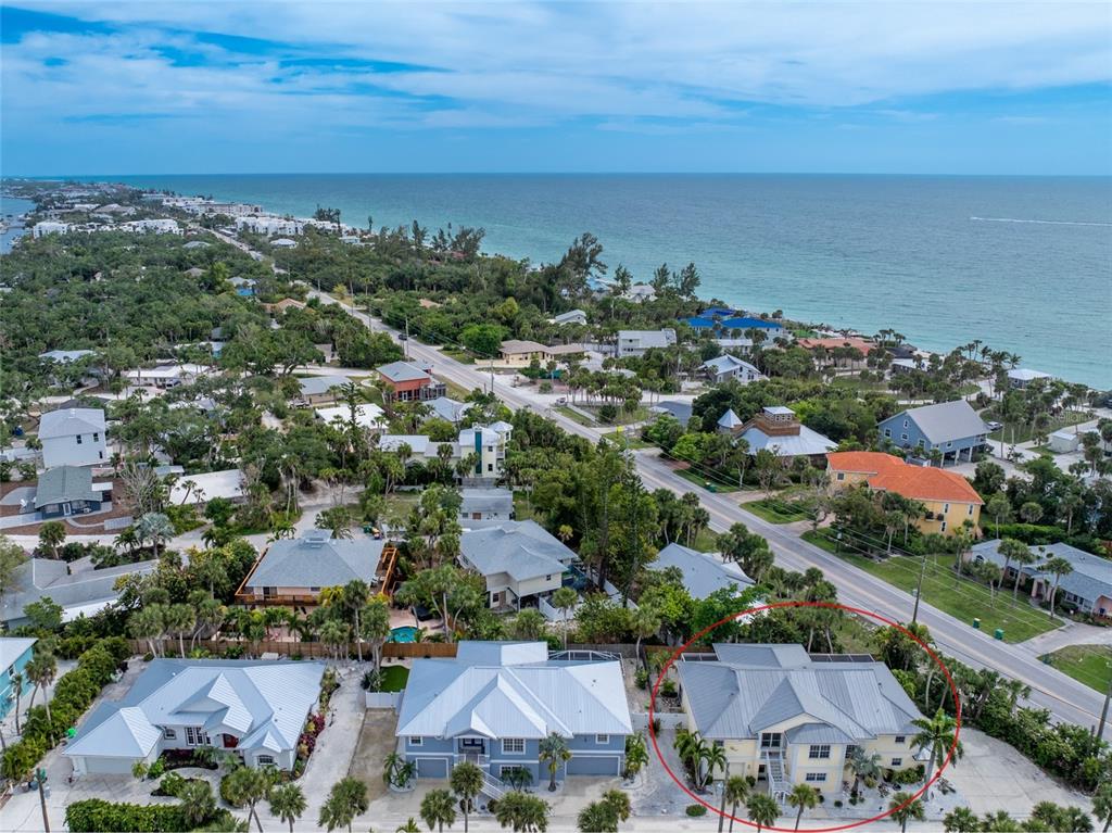 an aerial view of a city with lots of residential buildings and ocean view in back