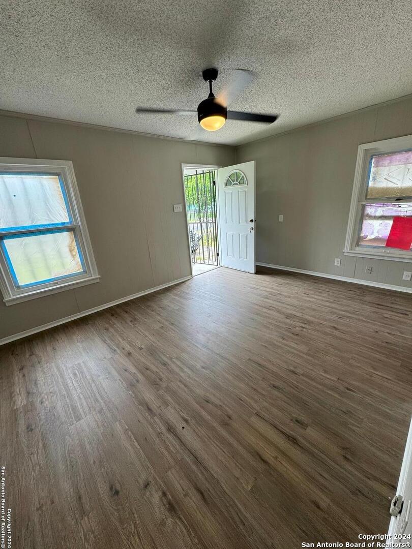 an empty room with wooden floor and windows