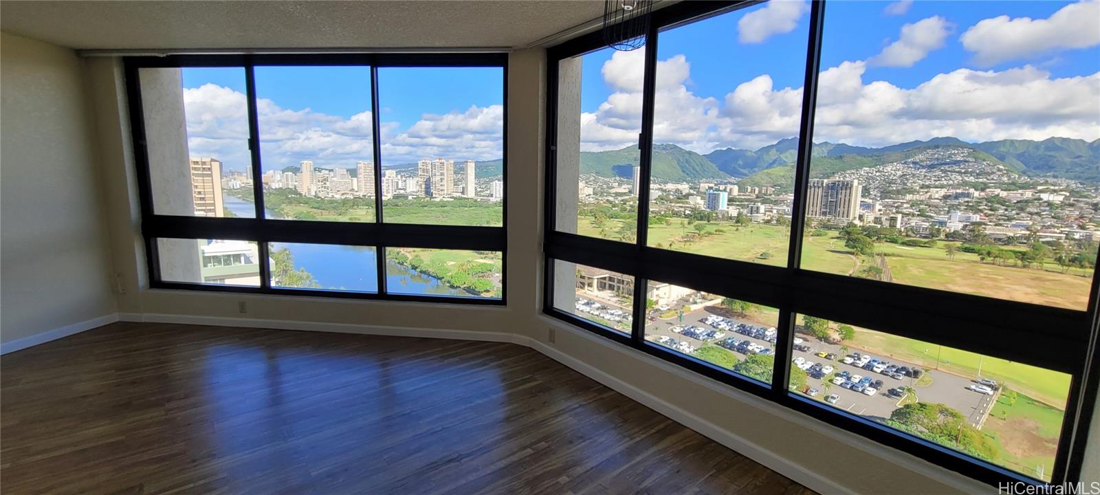 a view of an empty room with wooden floor and a window