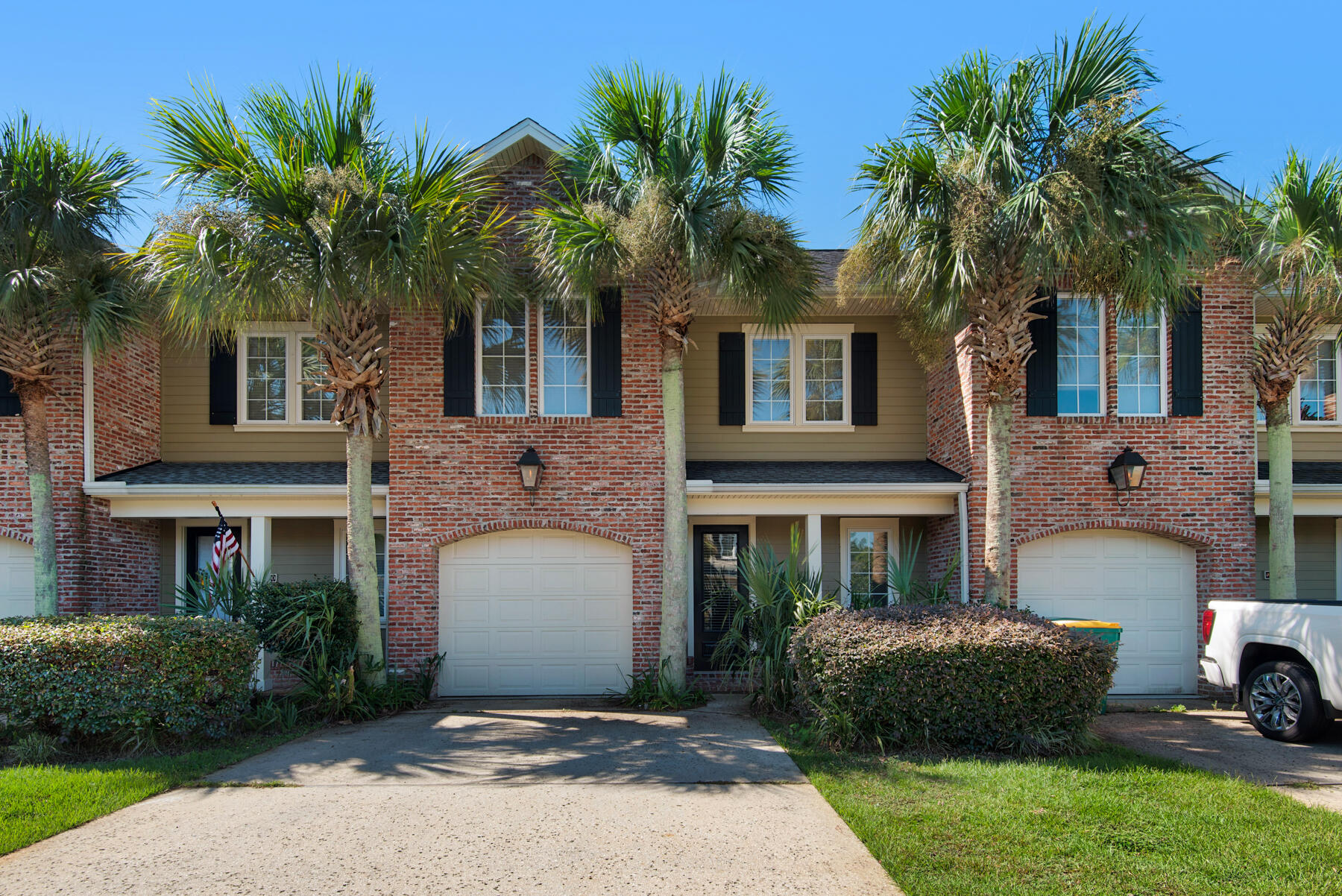 a front view of a house with a garden and palm trees