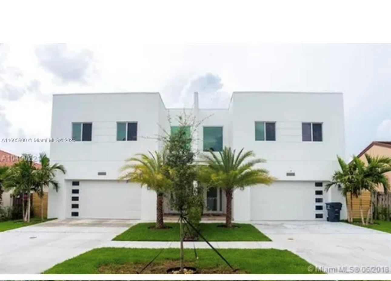 a white house with a yard and palm trees