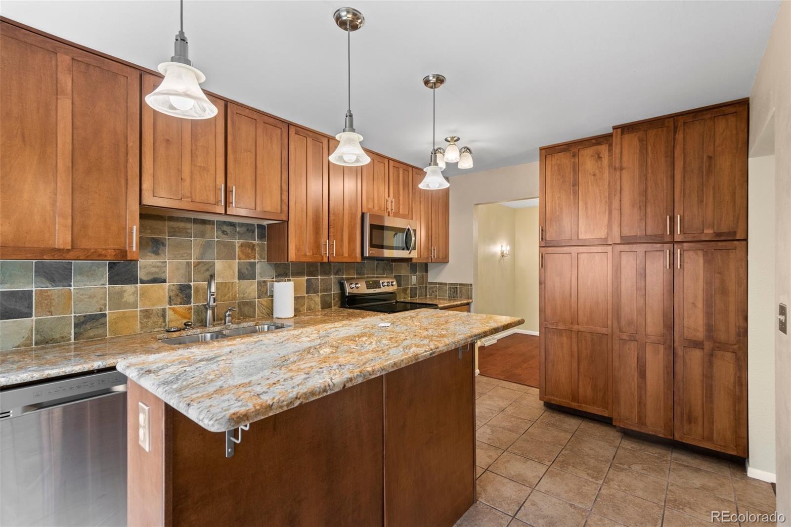 a kitchen with granite countertop a refrigerator a sink and wooden cabinets