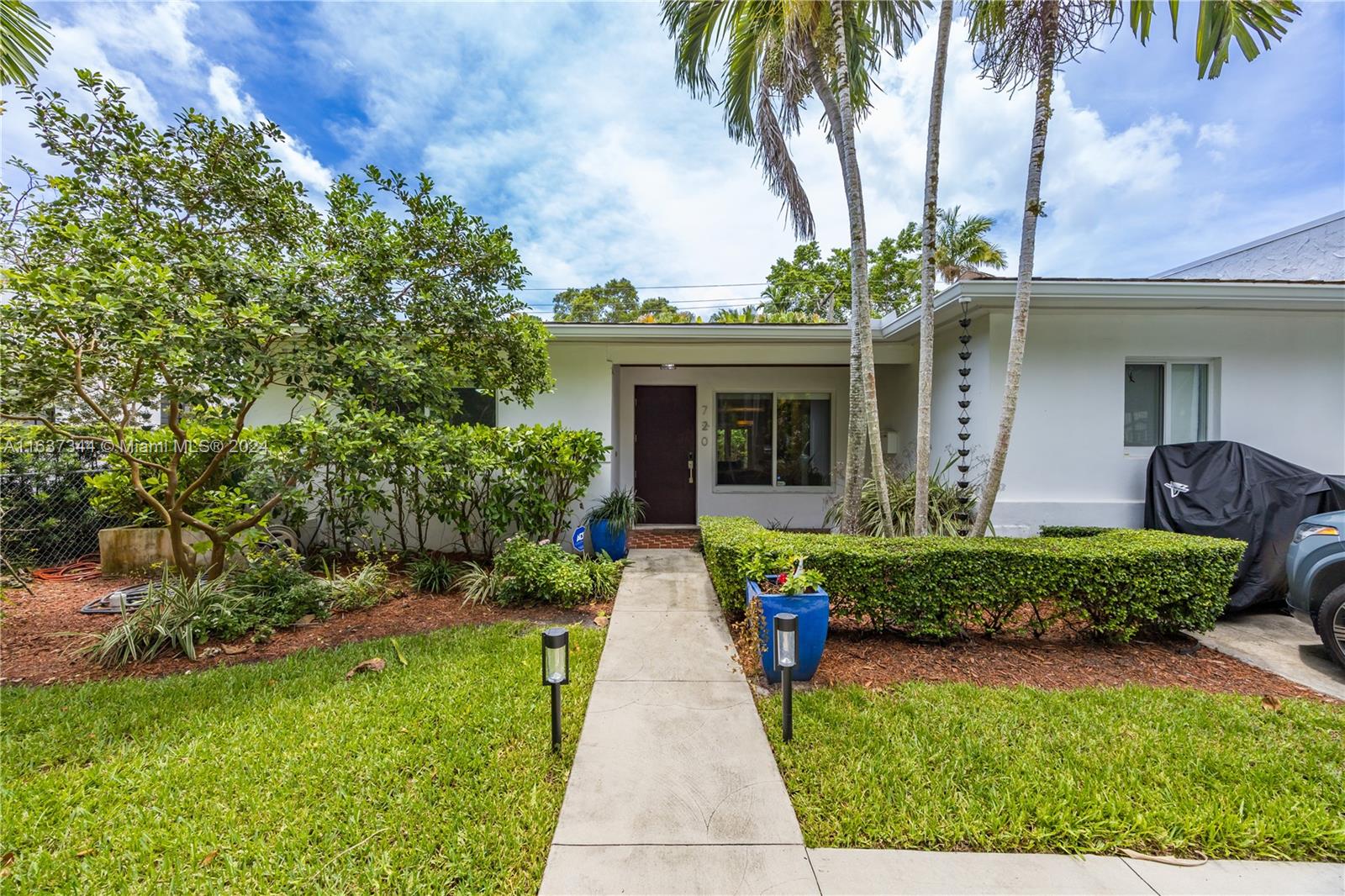 a front view of a house with a yard and potted plants