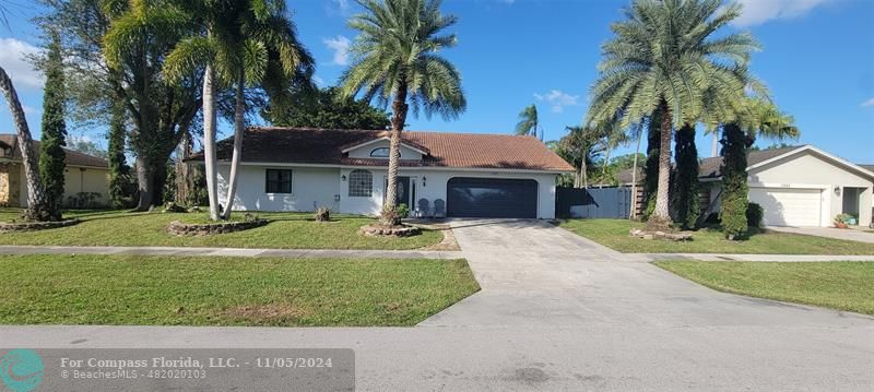 a front view of a house with a yard and palm trees