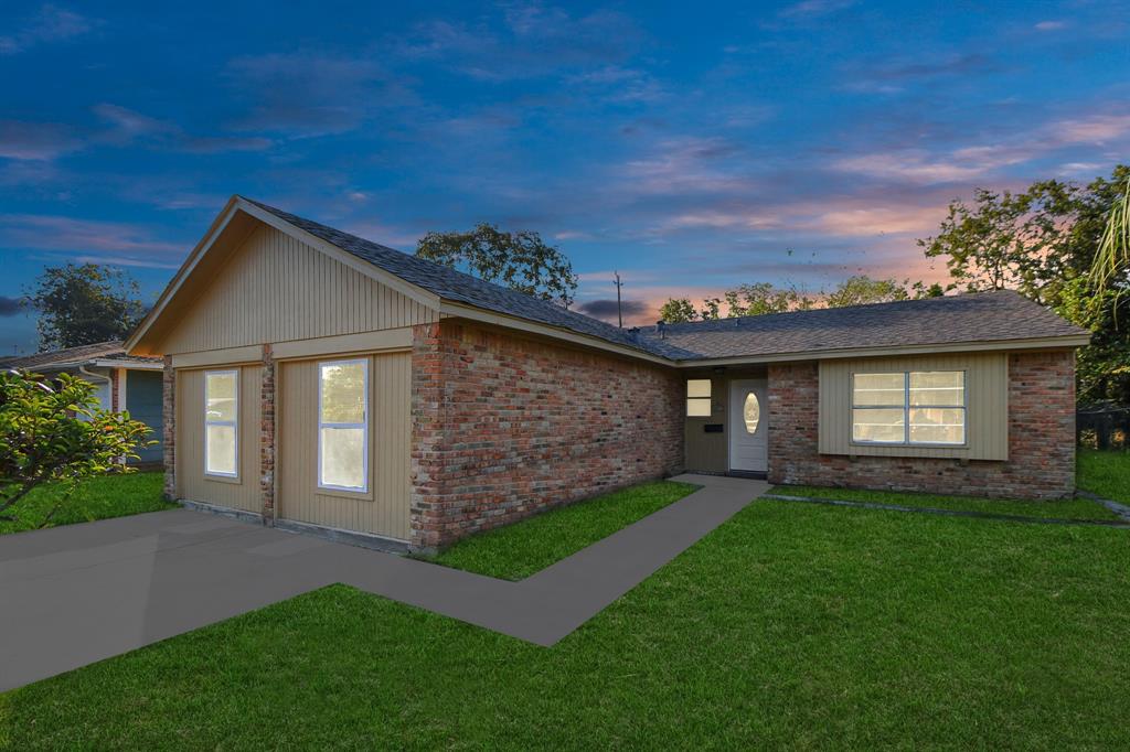 a brick house with a small yard and trees