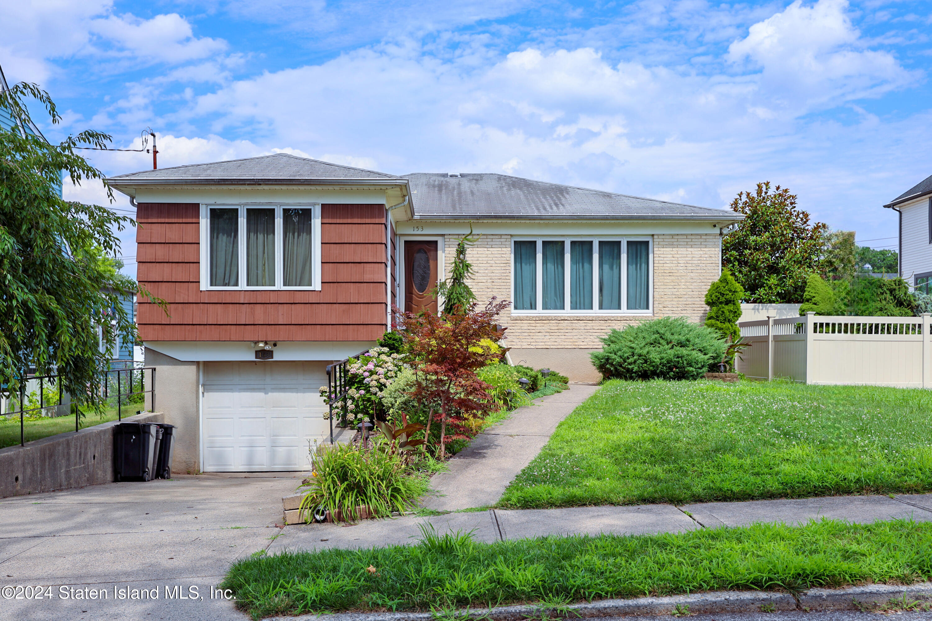 a front view of a house with a yard and potted plants