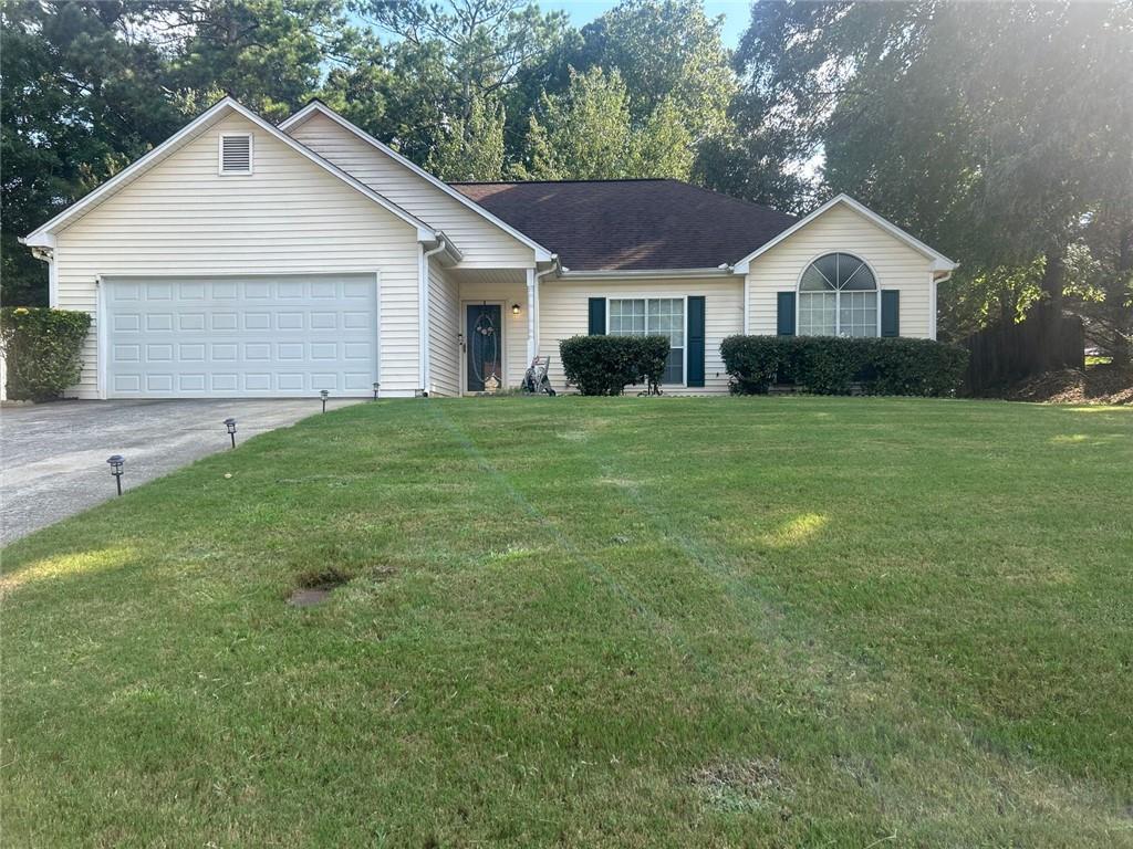 a view of a yard in front of a house with plants and large tree