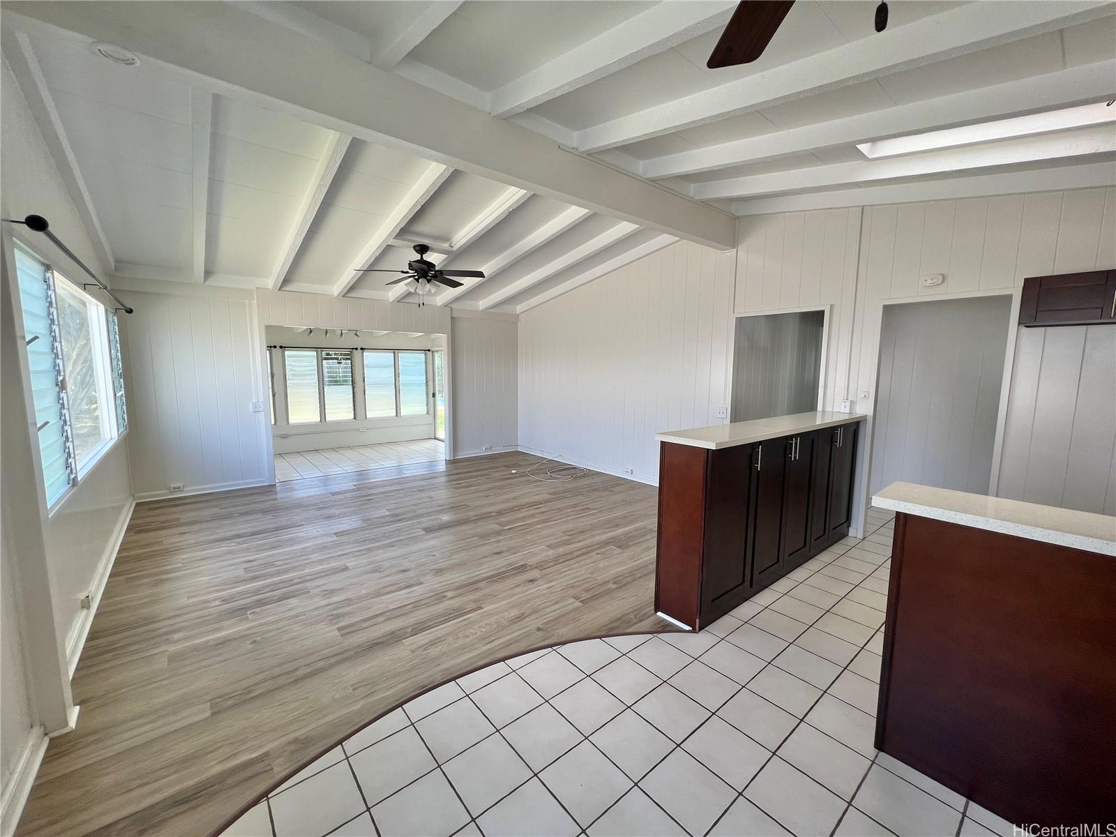 an empty room with wooden floor cabinet and windows