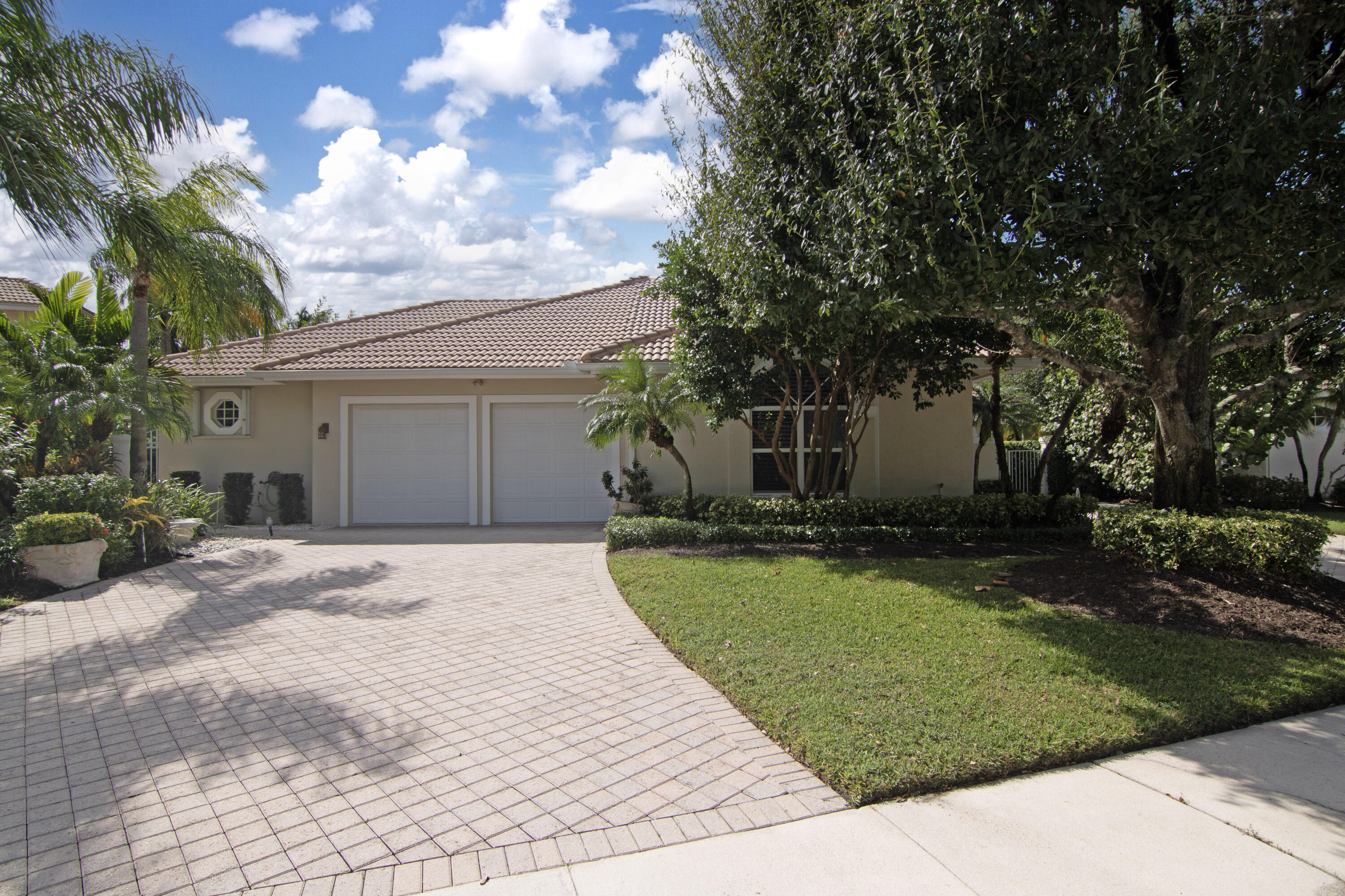 a front view of a house with a garden and trees