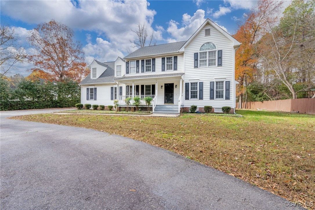 View of front of home with a front yard and a porc