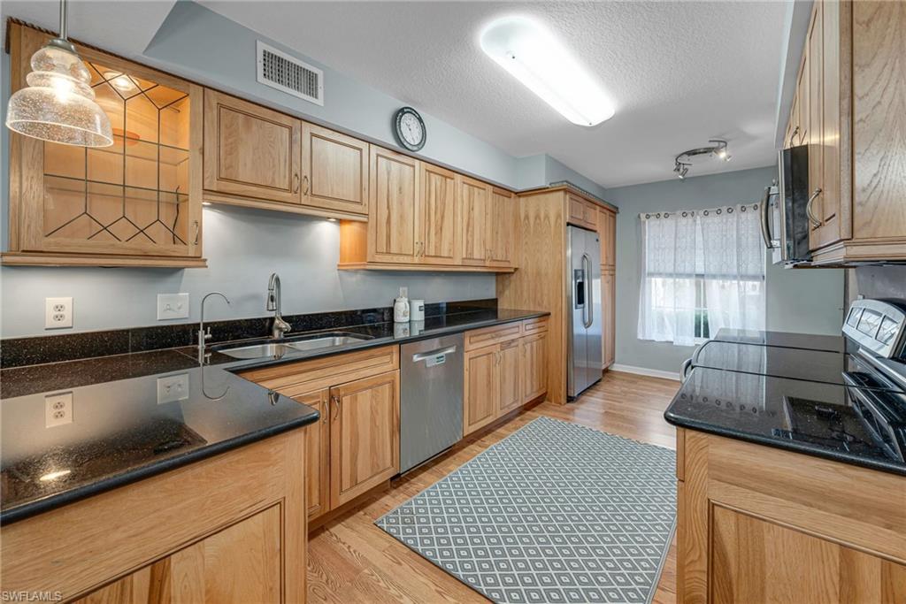 a kitchen with stainless steel appliances granite countertop a sink a stove and cabinets