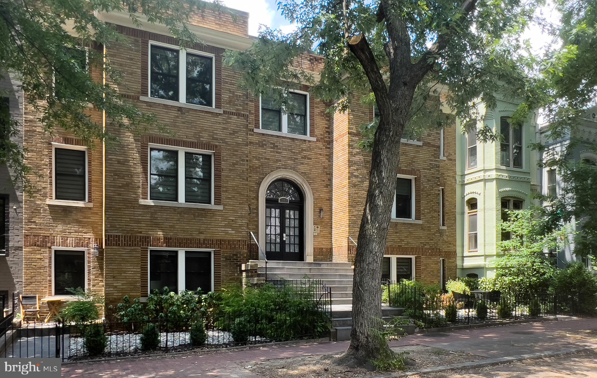 a front view of a house with plants and trees