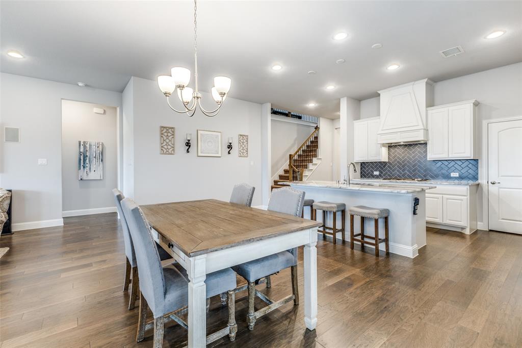 a kitchen with kitchen island a dining table chairs and white cabinets