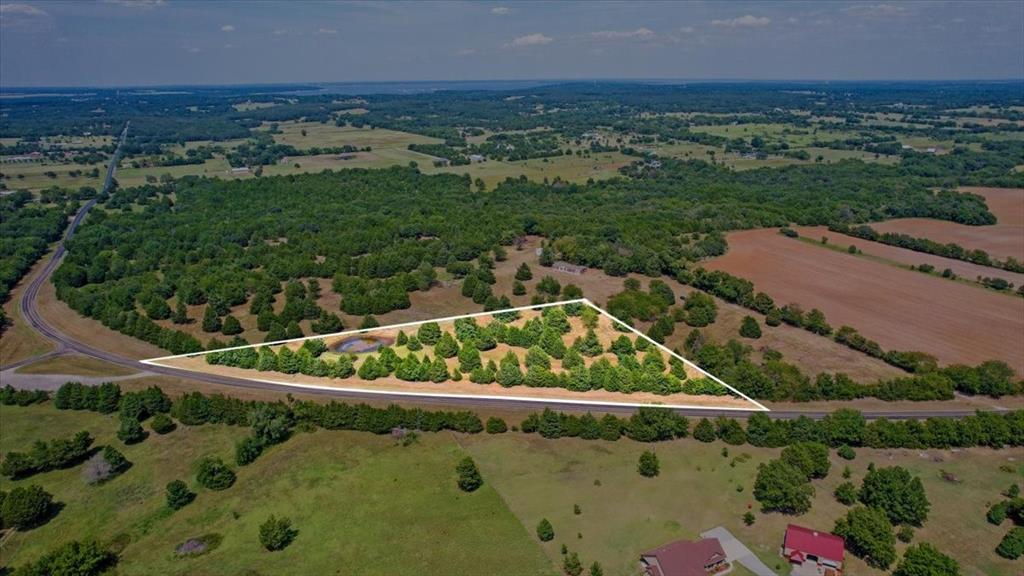 an aerial view of a residential houses with outdoor space and trees